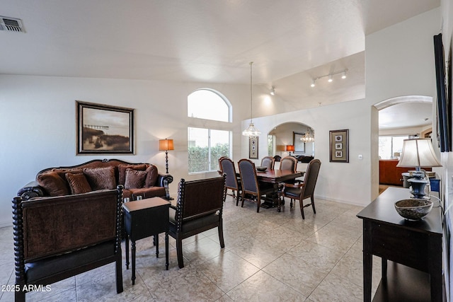 living area featuring visible vents, arched walkways, light tile patterned flooring, baseboards, and a chandelier