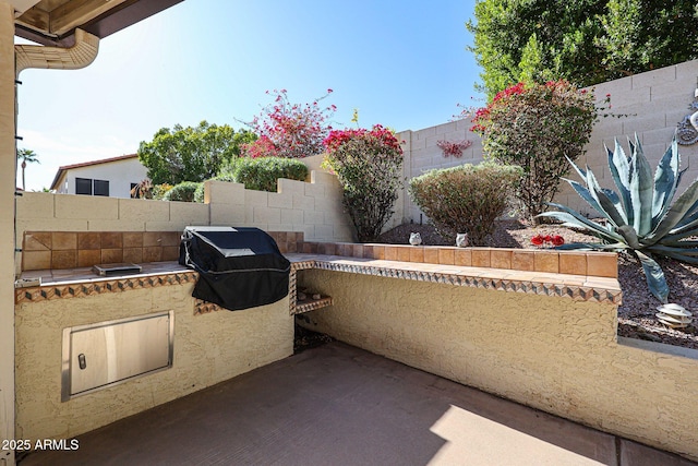 view of patio featuring exterior kitchen, a fenced backyard, and grilling area