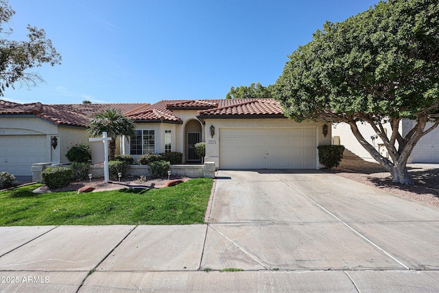 mediterranean / spanish house featuring stucco siding, concrete driveway, a front yard, an attached garage, and a tiled roof