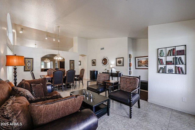 living room with arched walkways, a notable chandelier, baseboards, and vaulted ceiling