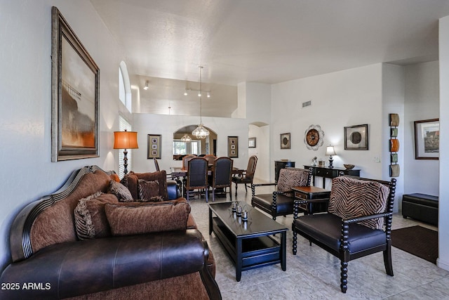 living area featuring arched walkways, light tile patterned floors, and high vaulted ceiling