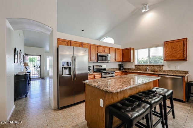 kitchen with a wealth of natural light, a kitchen island, stainless steel appliances, and brown cabinetry