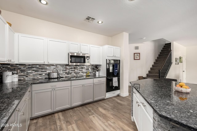 kitchen with white cabinets, double oven, and dark stone counters