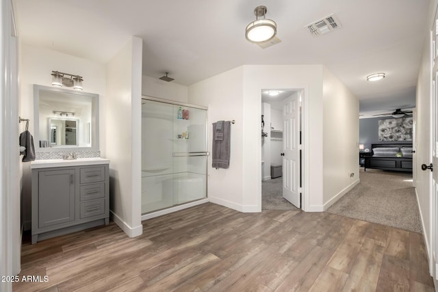 bathroom with vanity, hardwood / wood-style flooring, a shower with door, and ceiling fan