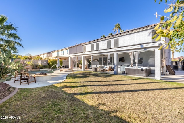 back of house featuring a lawn, an outdoor living space, a patio area, and a hot tub