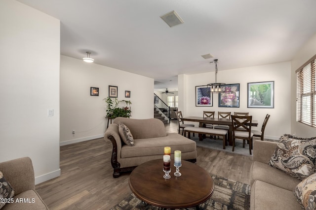 living room featuring ceiling fan with notable chandelier and hardwood / wood-style flooring