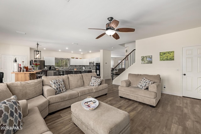 living room with dark hardwood / wood-style floors and ceiling fan with notable chandelier