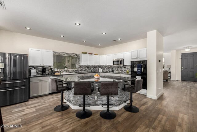 kitchen featuring dark stone counters, sink, appliances with stainless steel finishes, a kitchen island, and a kitchen bar