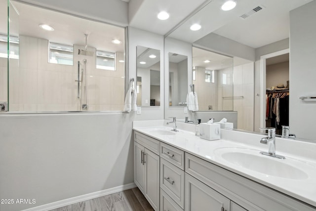 bathroom featuring double vanity, visible vents, walk in shower, and a sink