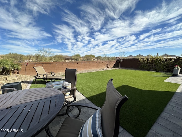 view of yard featuring outdoor dining space, a patio area, and a fenced backyard