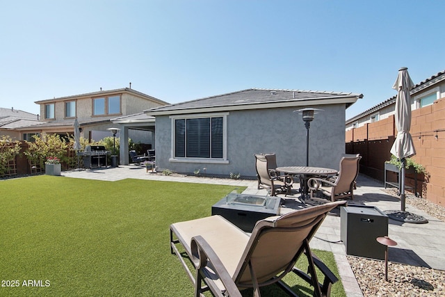 rear view of property featuring a patio area, a lawn, a fenced backyard, and stucco siding