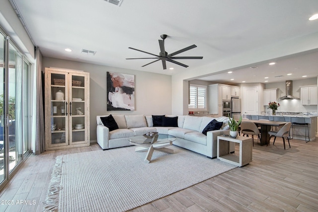 living area with visible vents, recessed lighting, light wood-type flooring, and ceiling fan