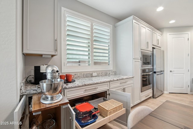 kitchen with light stone counters, light wood-style flooring, recessed lighting, stainless steel appliances, and white cabinets