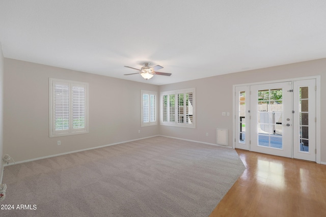 empty room with light wood-type flooring, ceiling fan, and a healthy amount of sunlight