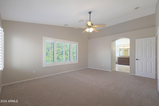 empty room with light carpet, vaulted ceiling, and ceiling fan