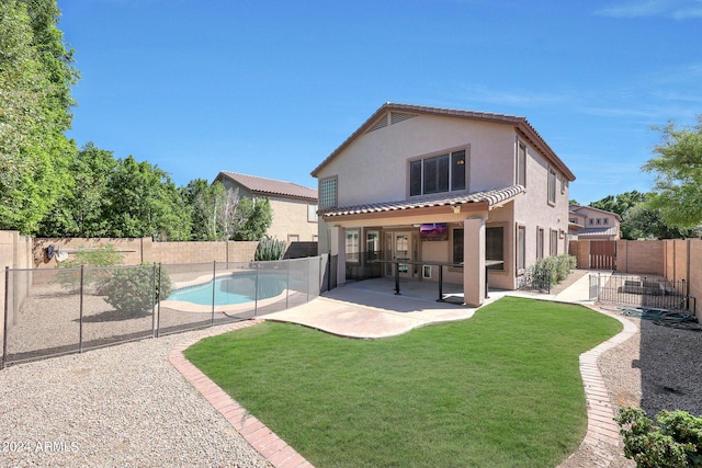 back of property with a fenced in pool, a patio area, and a yard