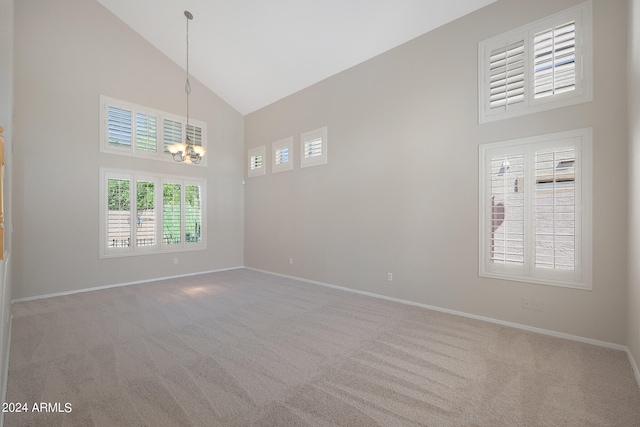 spare room with high vaulted ceiling, carpet floors, and an inviting chandelier