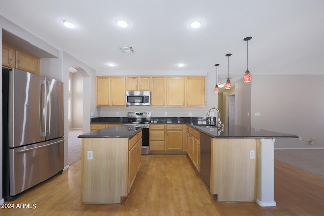 kitchen with light brown cabinets, sink, light hardwood / wood-style flooring, decorative light fixtures, and appliances with stainless steel finishes