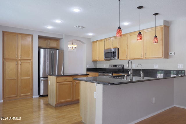 kitchen featuring pendant lighting, a notable chandelier, kitchen peninsula, light hardwood / wood-style flooring, and stainless steel appliances