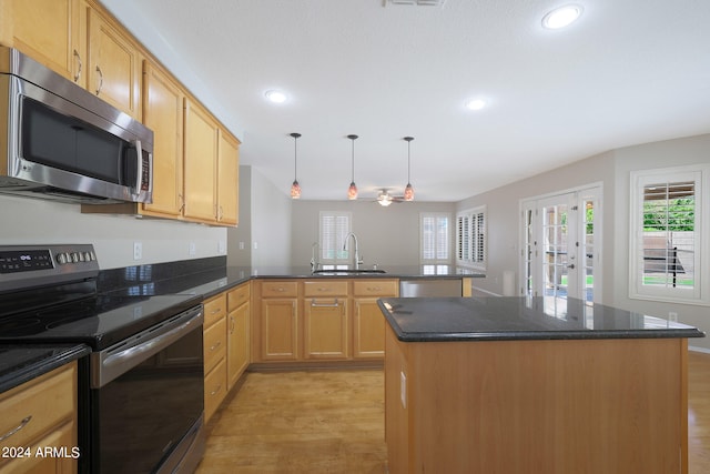 kitchen featuring light wood-type flooring, sink, kitchen peninsula, a kitchen island, and stainless steel appliances