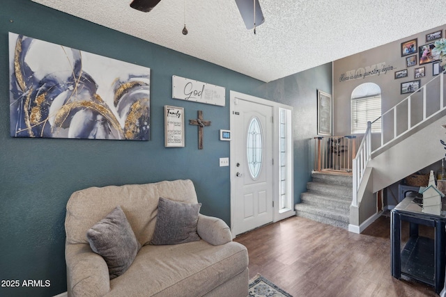 foyer entrance with baseboards, stairway, a textured ceiling, a ceiling fan, and wood finished floors