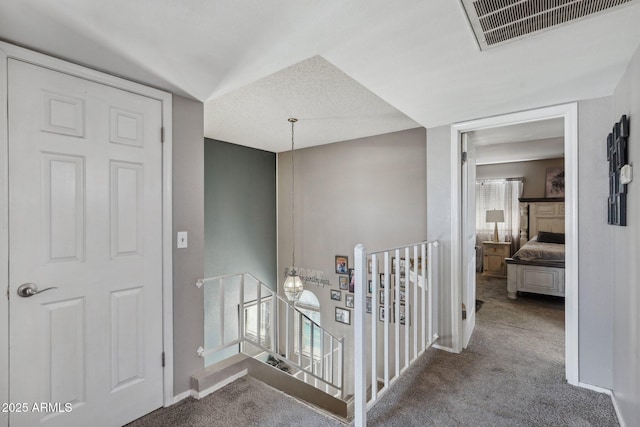 corridor with visible vents, baseboards, carpet, and an upstairs landing
