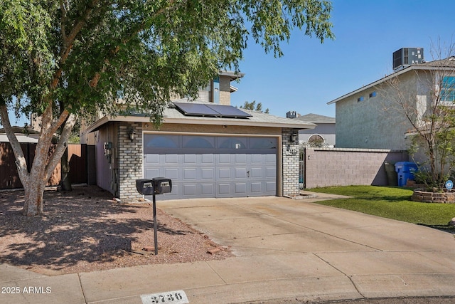 view of front of home with driveway, cooling unit, solar panels, a garage, and fence