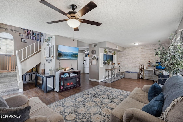living room featuring a textured ceiling, wood finished floors, ceiling fan, and stairs