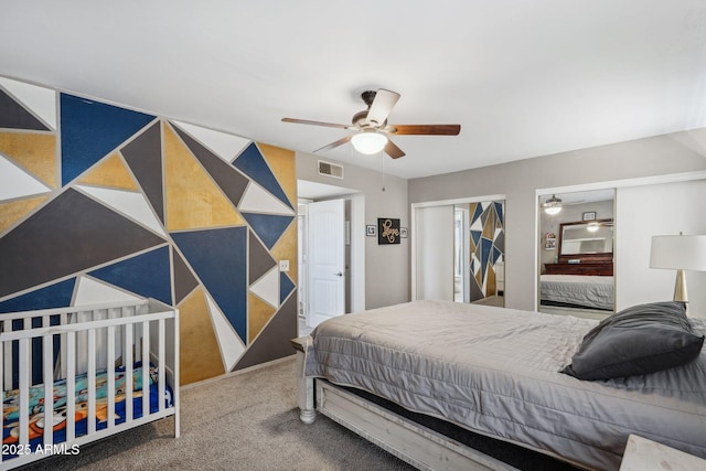 bedroom featuring carpet flooring, a ceiling fan, visible vents, and multiple closets