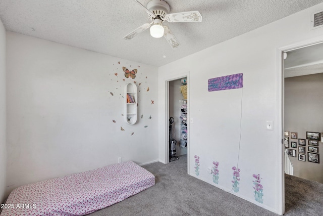 carpeted bedroom featuring a textured ceiling, a ceiling fan, and visible vents