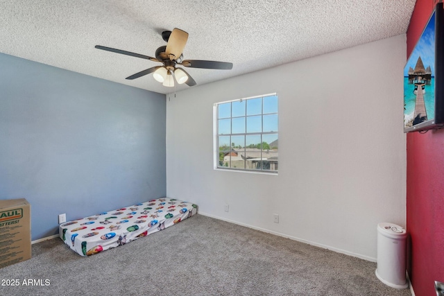 unfurnished bedroom with baseboards, carpet flooring, a textured ceiling, and a ceiling fan