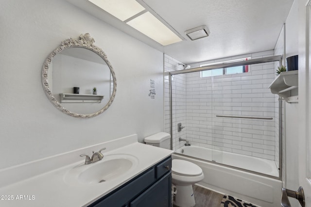 full bathroom with combined bath / shower with glass door, vanity, a textured ceiling, toilet, and wood finished floors