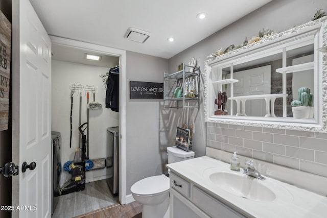 bathroom with tasteful backsplash, vanity, recessed lighting, toilet, and wood finished floors