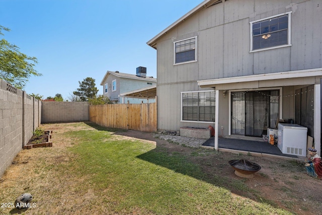 back of property featuring a yard, a fenced backyard, and central AC