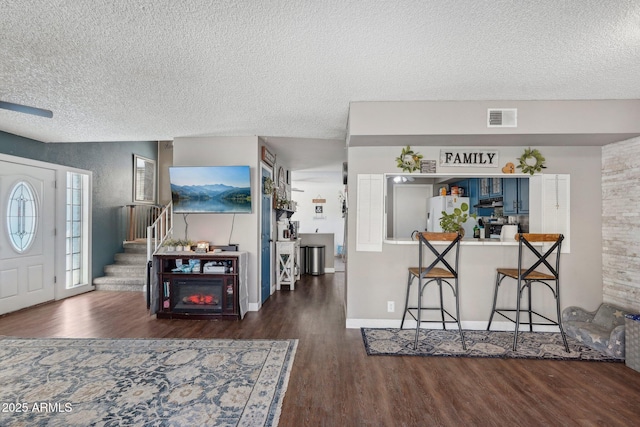 entrance foyer featuring a textured ceiling, wood finished floors, visible vents, and stairway