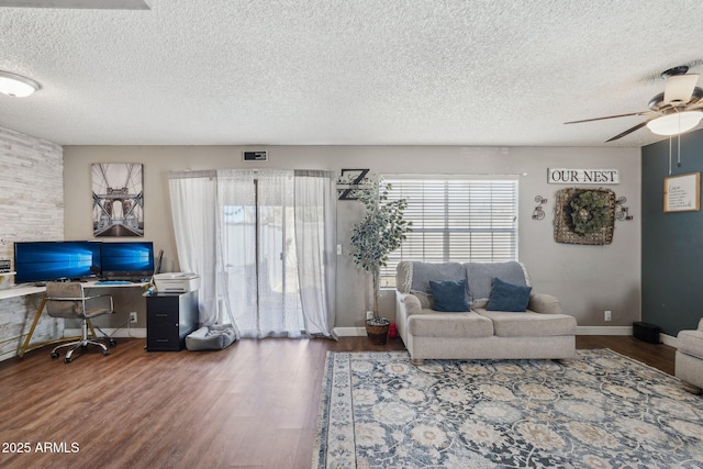 living room with ceiling fan, a wealth of natural light, wood finished floors, and a textured ceiling