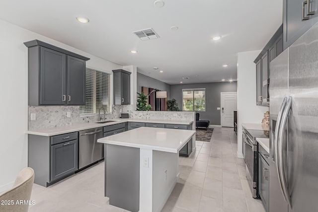 16877 W Butler Ave, Waddell, AZ 85355 - kitchen featuring stainless steel appliances, a sink, a peninsula, light countertops, and backsplash