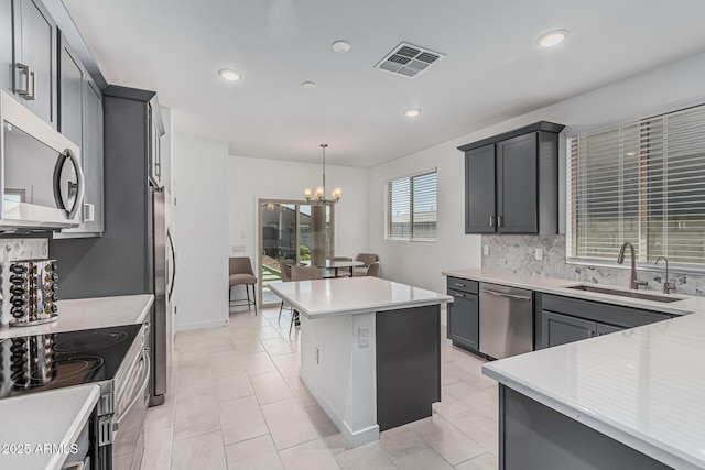 16877 W Butler Ave, Waddell, AZ 85355 - kitchen featuring stainless steel appliances, a sink, light countertops, backsplash, and a chandelier