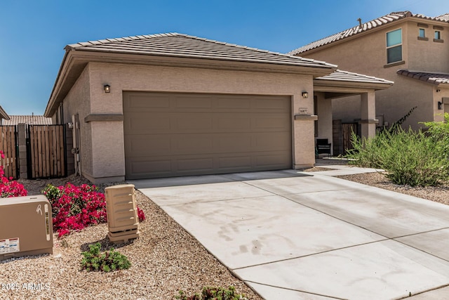 16877 W Butler Ave, Waddell, AZ 85355 - view of front facade featuring concrete driveway, a garage, a tiled roof, stucco siding, and a gate