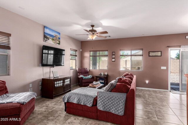 tiled living area featuring baseboards, a ceiling fan, and a wealth of natural light