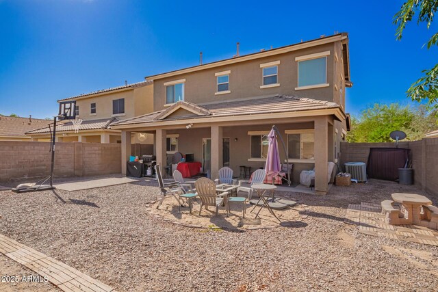 rear view of house featuring cooling unit, a fenced backyard, stucco siding, a patio, and a tile roof
