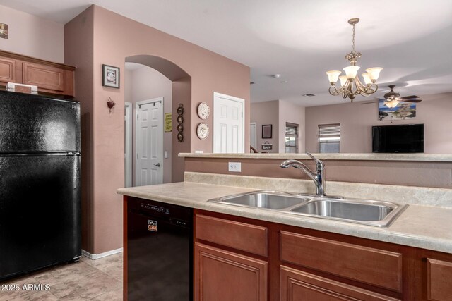 kitchen with hanging light fixtures, arched walkways, a sink, black appliances, and ceiling fan with notable chandelier