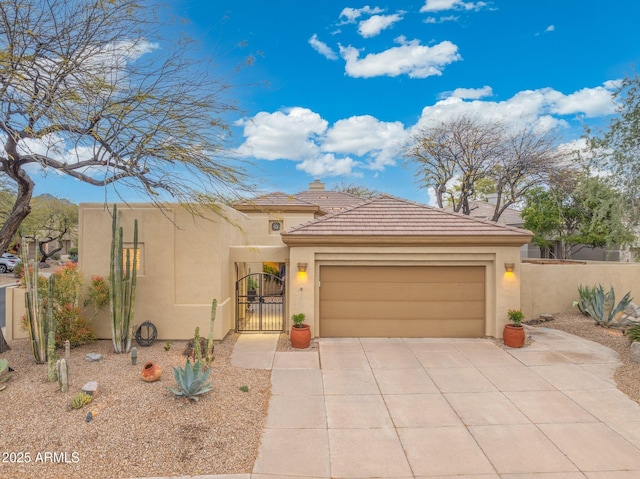 view of front of home with concrete driveway, stucco siding, a tiled roof, a gate, and a garage