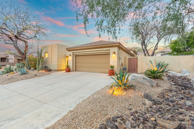 view of front facade with a tile roof, concrete driveway, stucco siding, fence, and an attached garage