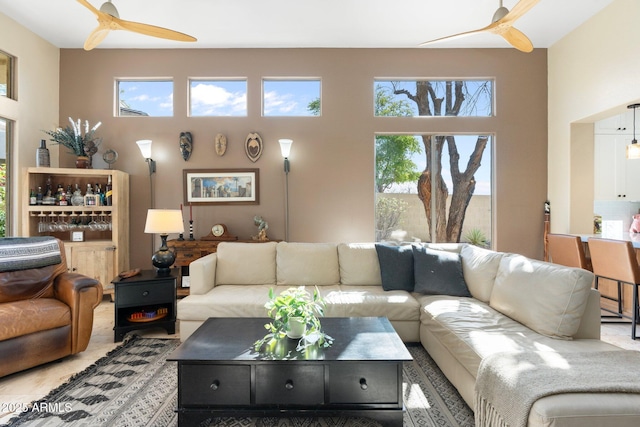 living room with a ceiling fan, plenty of natural light, and a towering ceiling
