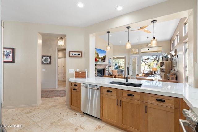 kitchen featuring a sink, a fireplace, light countertops, and dishwasher