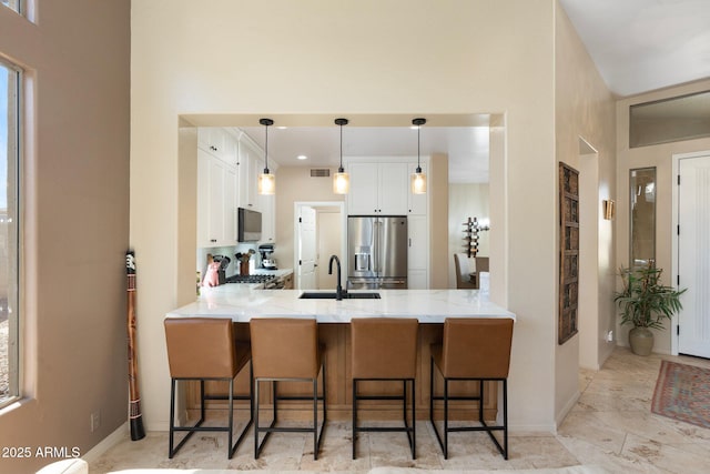 kitchen with white cabinetry, a sink, stainless steel appliances, and a peninsula