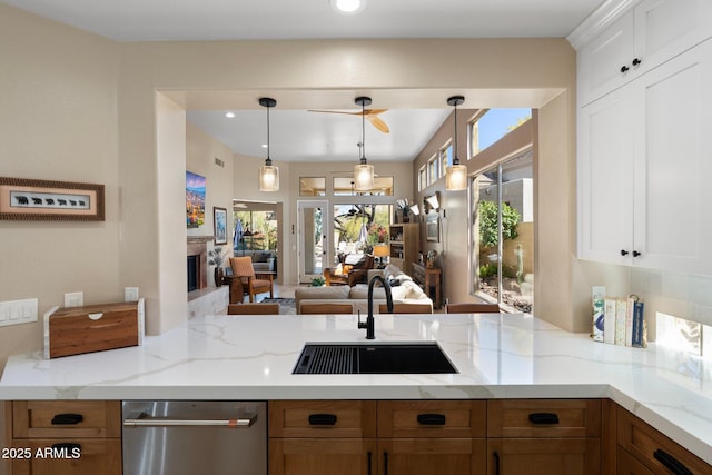 kitchen featuring a peninsula, light stone countertops, a sink, decorative light fixtures, and open floor plan
