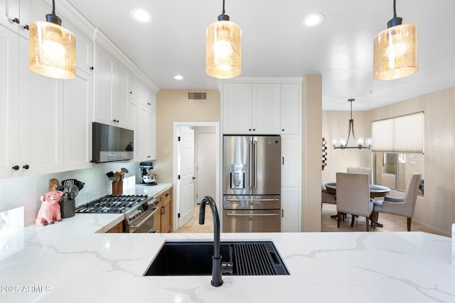 kitchen with a sink, stainless steel appliances, visible vents, recessed lighting, and an inviting chandelier