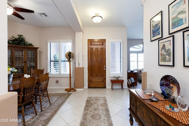 foyer entrance with light tile patterned floors, a wealth of natural light, and ceiling fan